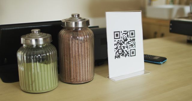 Spices in jars, plaque with qr code and smartphone lying on countertop. small independent cafe business.