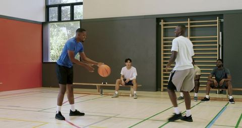 African american men dribbling and defending in one-on-one basketball drill indoor gym