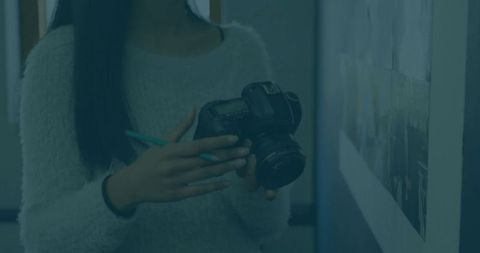Young photographer inspecting mounted print holding dslr camera and pen in classroom studio