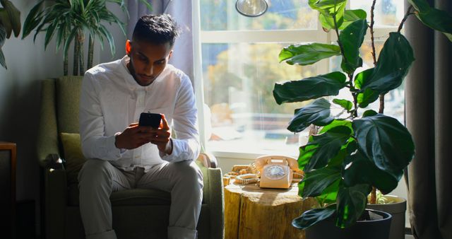 Man Using Smartphone Relaxing at Home near Window - Download Free Stock Images Pikwizard.com