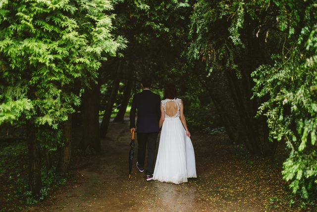 Couple walking through lush green forest, bride in white wedding dress and groom in suit. Ideal for images representing weddings, nature weddings, romantic walks, love, togetherness, bridal themes, and outdoor ceremonies.