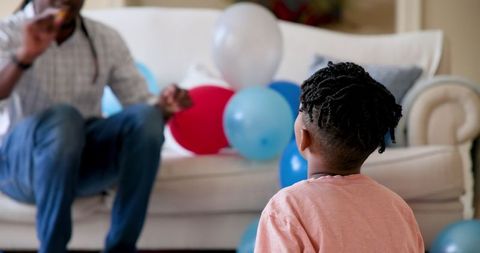 Father and Son Celebrating Birthday with Festive Balloons Indoors