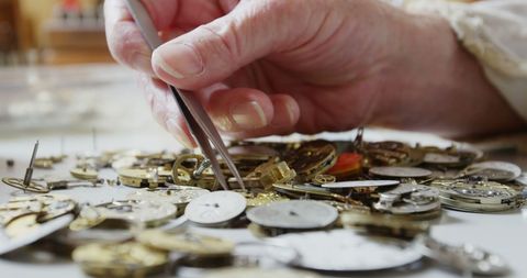 Horologist carefully handling watch parts with precision in workshop