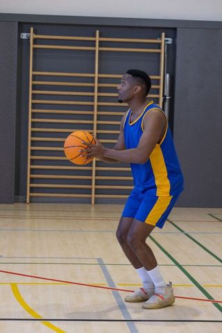 Focused Man Preparing Basketball Shot in Indoor Gym