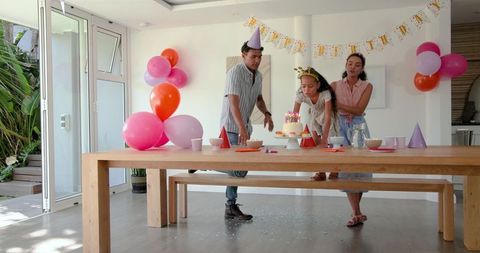 Family Celebrating Child's Birthday with Cake and Balloons at Home