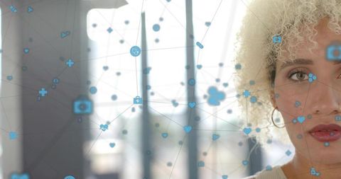 Contemporary woman gazing left by office window with blue medical network overlay for telehealth