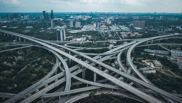 Aerial view of multilevel highway interchange connecting urban districts and skyline at dusk