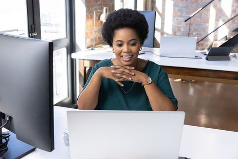Professional Woman Concentrating on Laptop in Modern Open Office