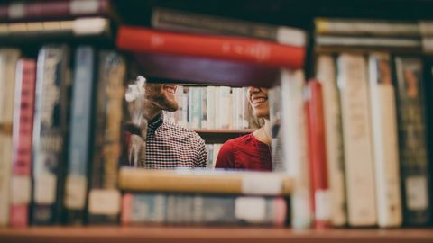 Smiling people behind bookshelf blurred edges full of books