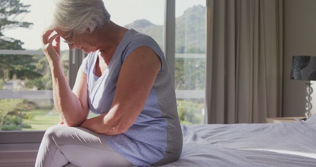 Pensive Elderly Woman Sitting on Bed Near Window in Sunlight - Download Free Stock Images Pikwizard.com