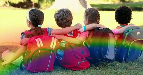 Diverse Children Sitting with Backpacks in Sunlight and Rainbow Effect