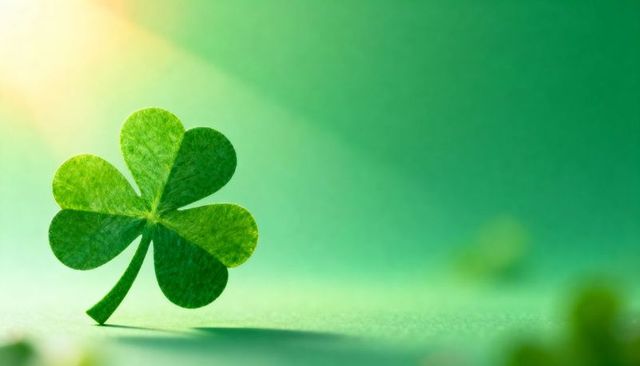 Standing four-leaf clover on emerald background with sun flare and soft bokeh