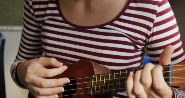 Woman Playing Ukulele Wearing Striped Shirt Indoors - Download Free Stock Images Pikwizard.com