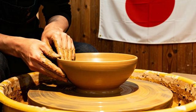 Potter hands shaping clay bowl on wheel in japanese workshop, throwing wet clay