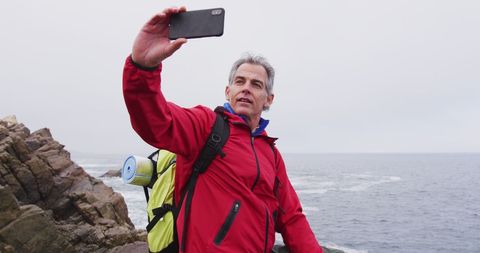 Senior Hiker Taking Selfie by the Sea Shore in Red Jacket