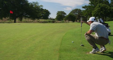 Golfer Carefully Lining Up Putt on Pristine Sunny Golf Course - Download Free Stock Images Pikwizard.com