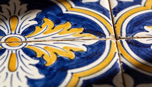 Decorative blue and yellow ceramic tiles highlighting central grout cross closeup sheen