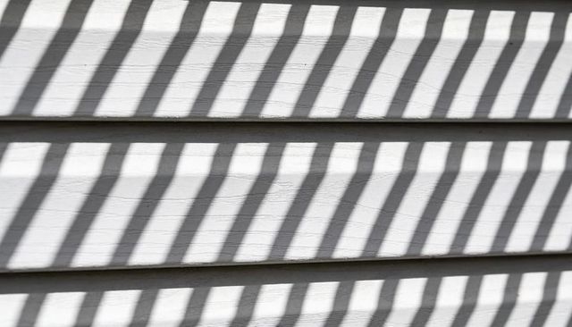 Casting Diagonal Sunlight Shadows on White Clapboard Siding Texture for Backgrounds