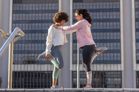 African american women stretching quads on urban steps during morning workout and warm up