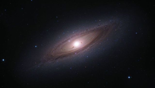 Rotating glowing spiral galaxy with tilted disk, dust lanes and dense star field
