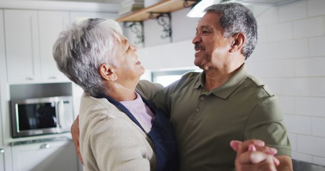 Happy senior biracial couple dancing in kitchen. Spending quality time at home, retirement and lifestyle concept.