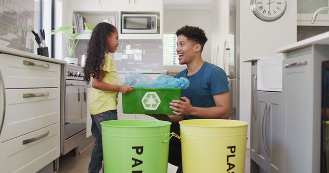 Father and daughter engaging in recycling activity in a modern kitchen. They are smiling and bonding while sorting recyclables. Ideal for illustrating concepts of family involvement in eco-friendly practices, promoting sustainability, and teaching children about waste management. Useful for articles, advertisements, or social media posts related to parenting, environmental awareness, and green lifestyle choices.