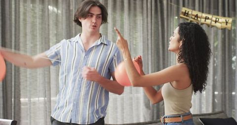 Couple preparing birthday party with balloon decorations indoors