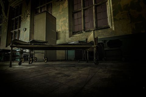 Abandoned hospital ward with empty bed in dark room