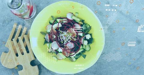 Overhead yellow salad bowl flatlay featuring radish cucumber beet greens with wooden board