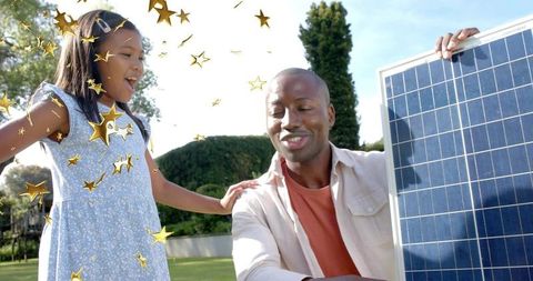 Dad installing solar panel in sunlit backyard with joyful child celebrating green energy