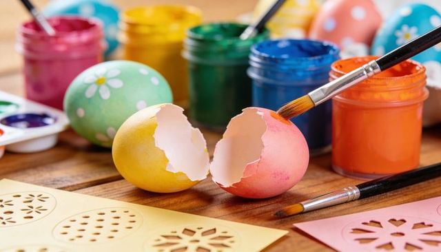 Spring easter egg decorating with cracked colorful eggshells, brushes and paint jars