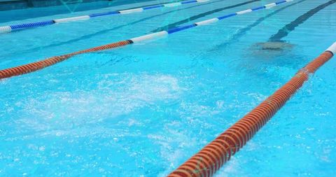 Outdoor swimming pool lanes stretching through clear blue water with colorful lane ropes
