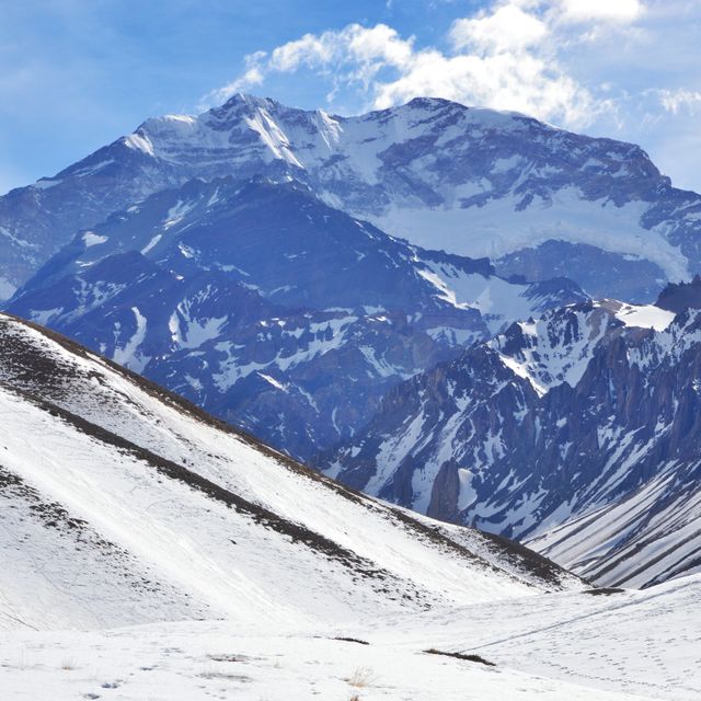 Mountain peak covered in snow against bright blue sky. Ideal for travel brochures, outdoor adventure promotions, nature calendars, and winter sport advertisements.