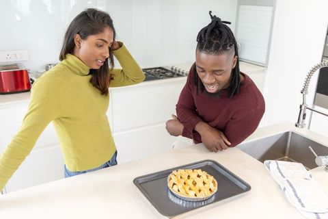 Couple admiring freshly baked lattice pie on bright modern kitchen island
