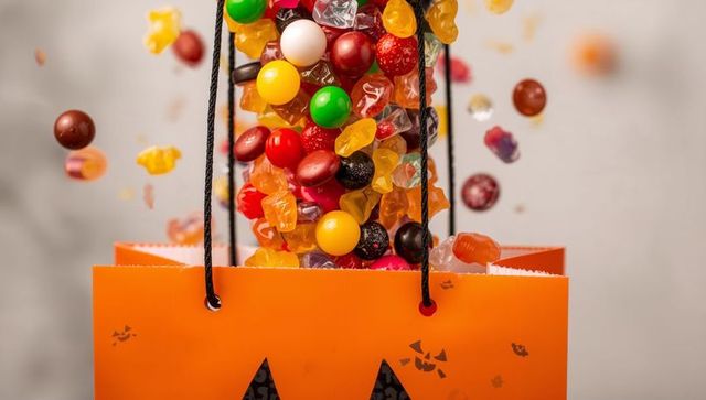 Colorful assortment of halloween candy pouring from festive bag