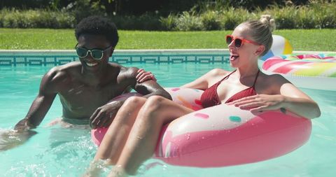 Joyful Couple Enjoying Fun in Sun at Backyard Pool with Donut Float