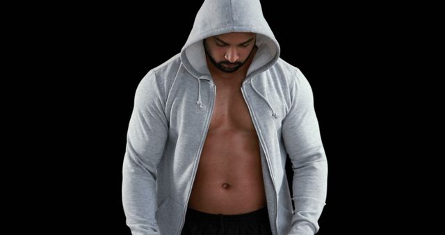 An athletic man showcases his muscular physique while wearing a gray hoodie. This image can be used for fitness motivation, gym advertisements, activewear promotional materials, and health and wellness blogs.