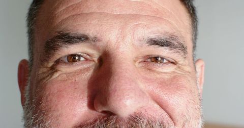 Closeup of mature man leaning toward camera, showing textured skin and graying beard