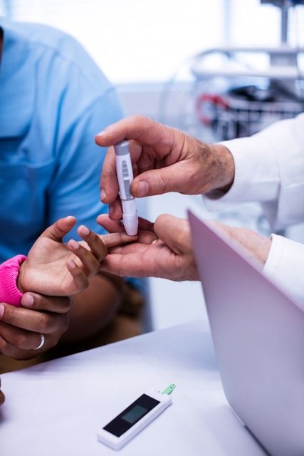 Doctor performing a blood sugar test on a patient's finger using a glucose meter in a hospital setting. This image can be used for healthcare articles, diabetes awareness campaigns, medical blogs, and educational materials about diabetes management and health monitoring.