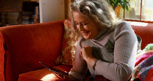 Middle-aged Woman Reading Tablet on Orange Couch in Cozy Sunlit Living Room - Download Free Stock Images Pikwizard.com