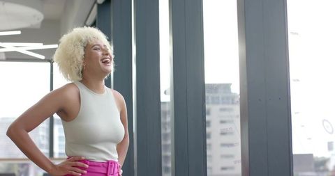 Confident professional woman laughing in modern office with city view