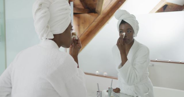 African american attractive woman removing make up in bathroom. beauty, pampering, home spa and wellbeing concept.