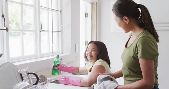 Image of happy biracial mother and daughter cleaning kitchen. Family, motherhood, relations and spending quality time together concept digitally generated image.