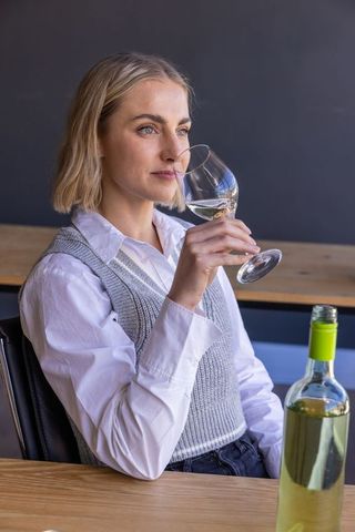 Woman Sits in Tasting Room Enjoying White Wine