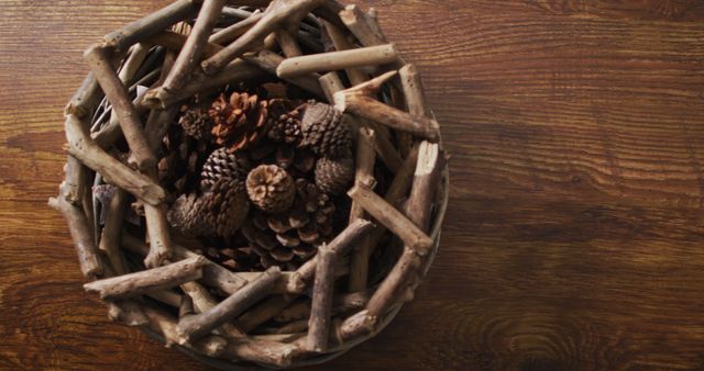 Wooden basket filled with pinecones sits on dark wooden table. Ideal for use in autumn-themed designs, nature-inspired settings, or rustic home decor promotions. Perfect for magazine spreads on seasonal decorations, photography related to natural elements, or advertisements for eco-friendly products.