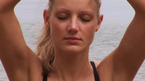 Young Woman Meditating on Beach in Tranquil Setting