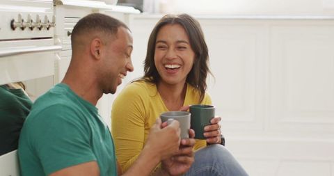 Smiling biracial couple enjoying coffee break in kitchen