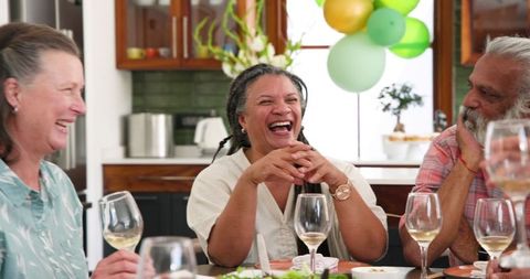 Multiracial senior friends enjoying laughter at dinner gathering