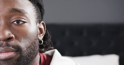 African american man closeup with dreadlocks, nose ring and hoodie in modern bedroom