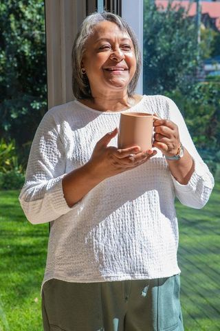 Senior Woman Relaxing With Coffee by Sunny Window